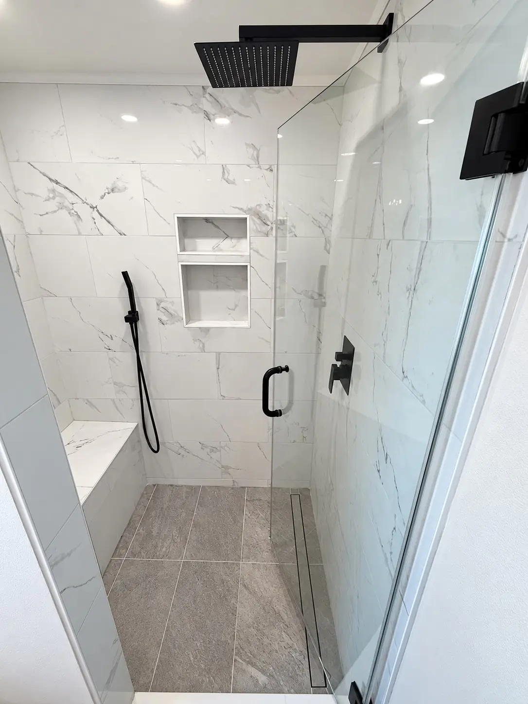 Prestige bathroom remodel with tiled shower, glass enclosure, built-in bench, and black fixtures