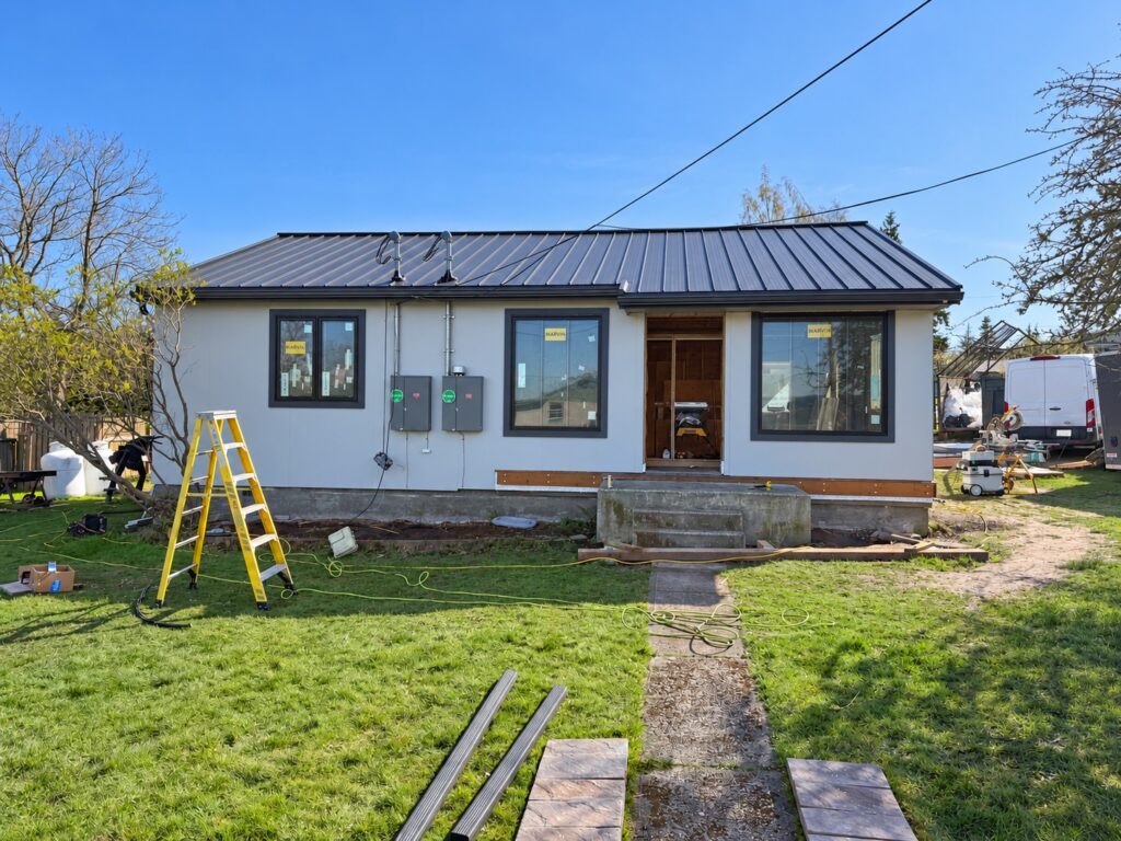 Prestige home renovation in progress with new windows, light siding and a standing-seam metal roof