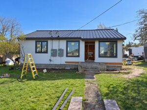 Prestige home renovation in progress with new windows, light siding and a standing-seam metal roof